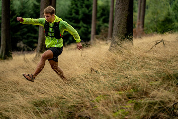 A young athlete in barefoot shoes runs down the mountain. Mountain run. Cross Country Running. Individual sports