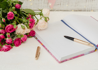 Goal planning concept. Open notebook on the table, pen and roses