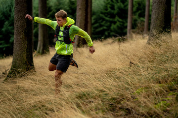 A young athlete in barefoot shoes runs down the mountain. Mountain run. Cross Country Running. Individual sports
