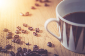 Close up of fresh roasted coffee beans and coffee mug on wooden background