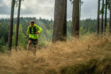 Obraz premium A young athlete in barefoot shoes runs down the mountain. Mountain run. Cross Country Running. Individual sports