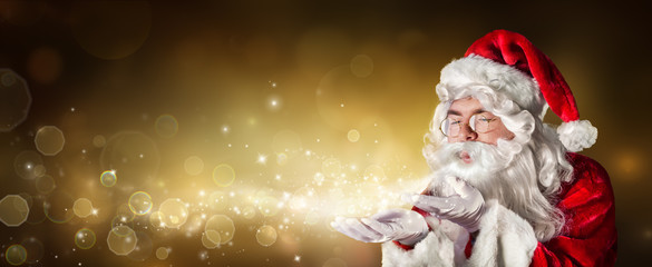 Santa Claus Blowing Magic Christmas Lights In Golden Background