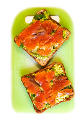 A sandwich with avacado and red fish, salmon lies on a green board. Healthy diet. Isolate vertical photo