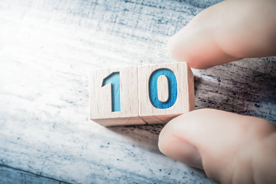 Number 10 Formed By Wooden Blocks And Arranged By Male Fingers On A Table