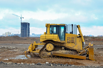 Bulldozer during of large construction jobs at building site. Land clearing, grading, pool excavation, utility trenching and foundation digging. Crawler tractor,  dozer, earth-moving equipment.