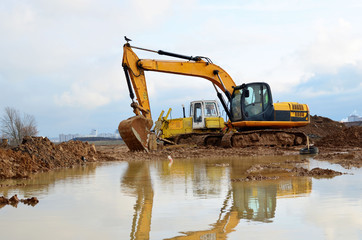 Tracked excavator working at a construction site during laying or replacement of underground storm...