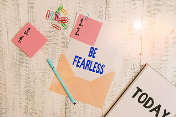Word writing text Be Fearless. Business photo showcasing act of living in spite of those things that scare you to death Envelope sheet paper sticky notes ballpoint notepad clips wooden background