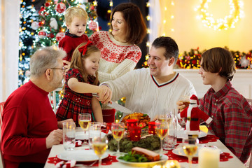 Family with kids having Christmas dinner at tree