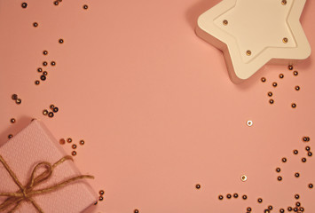 Blurred festive pink background with gold sparkles, white star and gift box. Copy spase. Festive moment