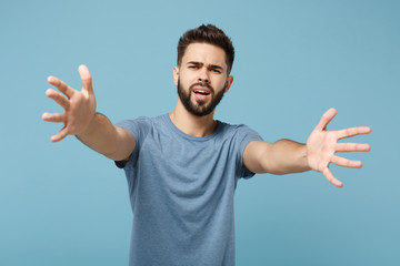 Young perplexed displeased man in casual clothes posing isolated on blue background, studio portrait. People sincere emotions lifestyle concept. Mock up copy space. Standing with outstretched hands.