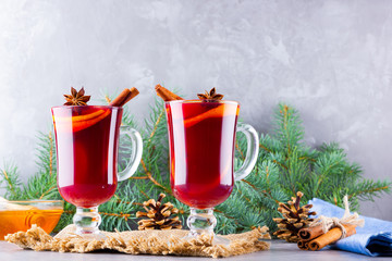 Mulled wine and fir branches on burlap. Mulled wine with oranges, honey, cinnamon and cloves on cement background. Hot wine with honey and spices