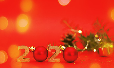 2020 New year golden number with sparkling festive christmas lights bokeh and tree branch, red...