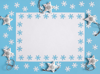 Christmas mockup with white snowflakes and stars on pastel blue background. Space for text. Greeting card. Winter concept.