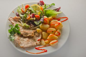 A plate of steak with french fries and salad