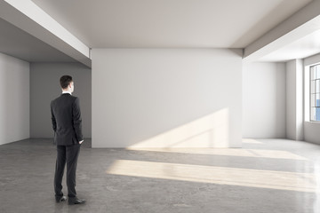 Fototapeta premium Businessman looking at blank wall