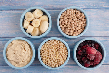 ingredients for making smoothies in bowls - frozen berries, banana, hummus, chickpea and pine nuts
