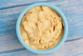 fresh hummus in a blue bowl on a blue background