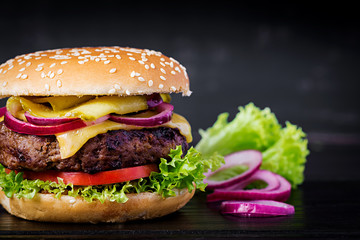 Big sandwich - hamburger burger with beef,  tomato, cheese, pickled cucumber and red onion.