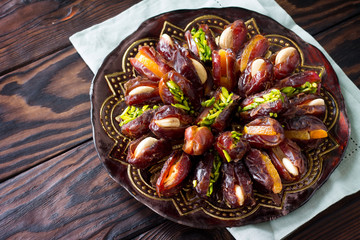 Dried dates stuffed with candied fruits and nuts on a rustic wooden table with copy space.