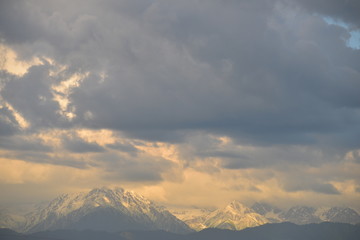 Naklejka na ściany i meble North caucasus mountains in the rays of light around clouds. Snowy mountain ridge peaks.