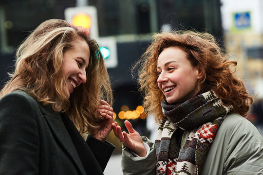 Two girls chatting on the street of the Moscow city happy and laughing