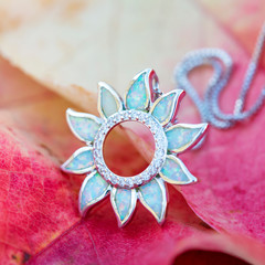 Silver pendant with white opal mineral stone on autumn background