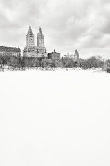 Fototapeta na wymiar Bleak monochrome view of the Upper West Side skyline above the frozen Central Park Lake after a winter storm in New York City