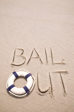 Business "Bail Out" message handwritten with lifesaver in smooth sand copy space