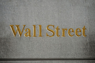 Close-up of gold Wall Street sign etched into a traditional stone wall in the Lower Manhattan Financial District in New York City