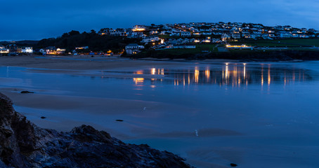 Polzeath, Cornwall /England UK: late evening view with the lights reflected in the wet sand. 