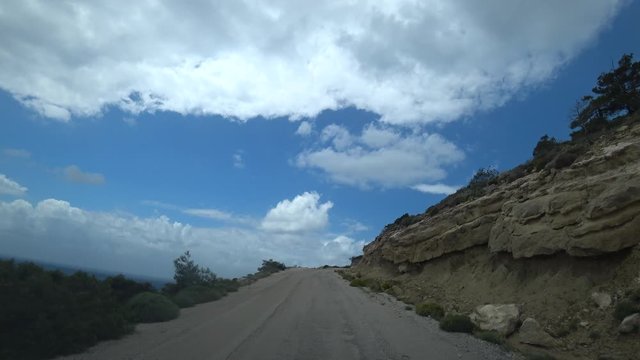 POV car driving shot. Climbing uphill along a narrow winding and broken road. The view from the car
