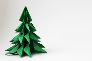 Origami green tree in the left corner of the photo on a white background