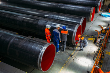 Engineers examine new coated pipe in factory