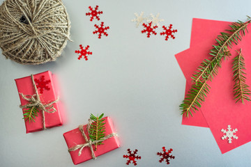 Christmas background with gift boxes, clews of rope, paper and decorations on red. Preparation for holidays, copy space.