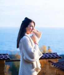 young girl in a white cardigan admires a morning sea view from a top of the fortress