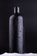 Black shampoo bottle on black background