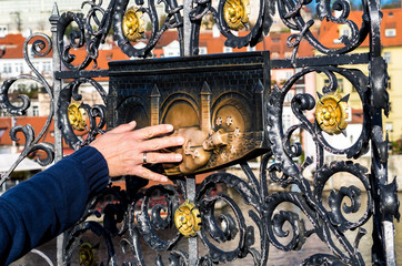 Hand Touches Bronze Sculpture Of Saint John Of Nepomuk On Charles Bridge In Prague In The Czech Republic