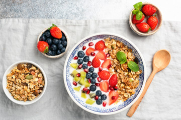 Healthy breakfast yogurt bowl with berries blueberry, strawberry, kiwi, pomegranate and granola on...