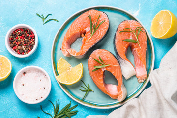 Raw salmon steak on blue top view.