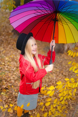 Image of sweet blond girl with long hair, closeup portrait of cute seven years old smiling girl with colorful umbrella. Outdoor autumn.