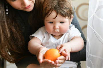 Fototapeta na wymiar Mom gives an orange to a child. vitamins to the child. fruit for children. healthy nutrition