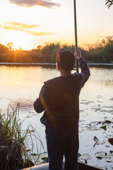 Boy fisherman catches fish on the shore of the pond at dawn.