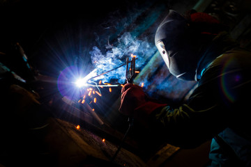 Fototapeta na wymiar welder doing metal work at night, front and background blurred with bokeh effect
