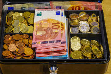 a small cash box full of coins and many banknotes