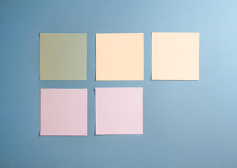 5 blank empty white and pastel colors sticky notes on clean blue background with free space, from...