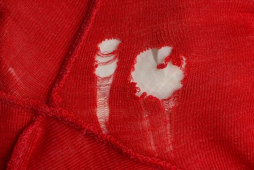 white holes on the red fabric of clothing with a seam