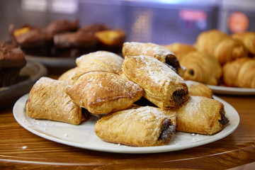 Buns with chocolate sprinkled with powdered sugar lie on a plate