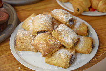 Buns with chocolate sprinkled with powdered sugar lie on a plate