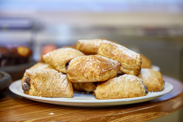 Buns with chocolate sprinkled with powdered sugar lie on a plate