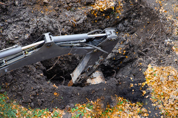 Yellow tractor excavator digs a pit with a bucket, accident. Breakthrough underground. Autumn...